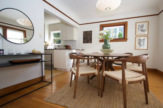 Dining room with a round table, chairs and a view into the adjoining room.