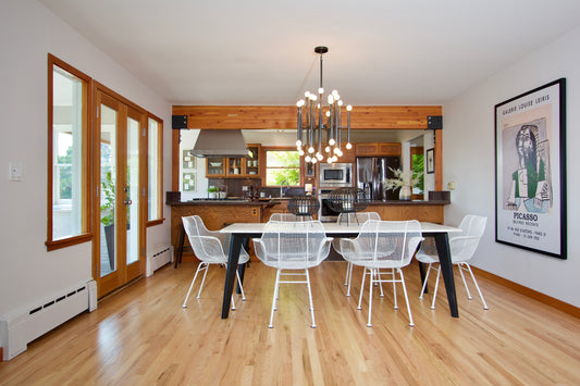 Dining table with white chairs, an adjoining kitchen and contemporary artwork.