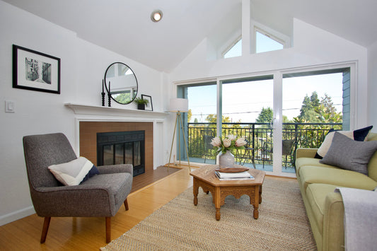 Furnished living room with a sofa and armchair beside broad windows.