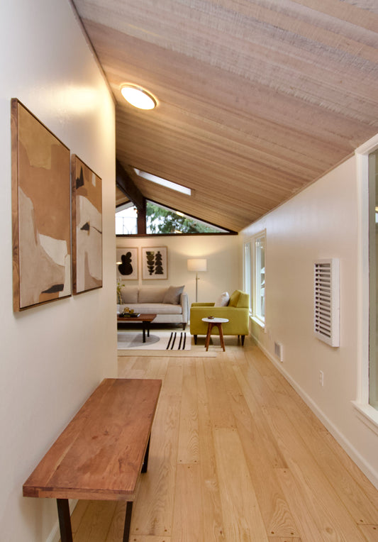 Wood bench along a hallway leading into a furnished living area.