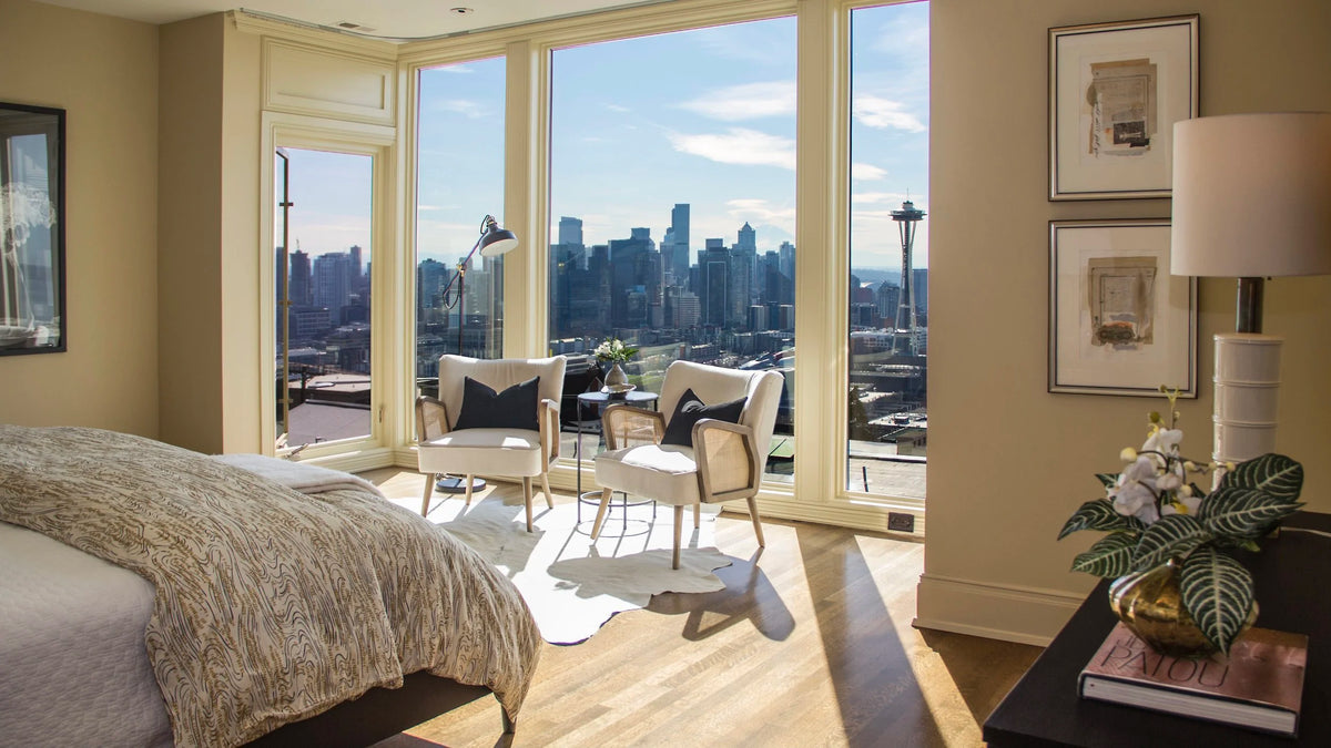The Seattle skyline and Space Needle beyond a sunlit bedroom and seating area staged by Nob Hill Style.